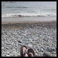 thumbnail pic of someone sitting by the ocean shore